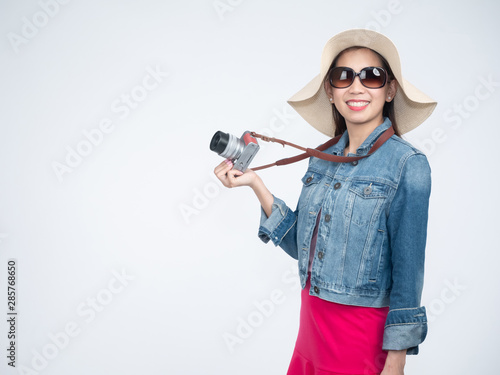 Portrait of beautiful asian woman with long hair in casual dress smiling cheerfully. Traveler tourist woman in jeans jacket holding camera on grey background.