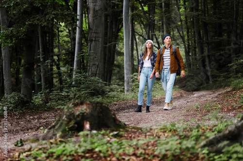 Caucasian couple of friends walking with backpacks in forest
