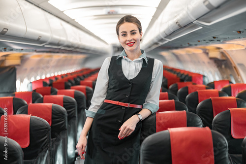 Caucasian attractive stewardess is on duty on board of airplane photo