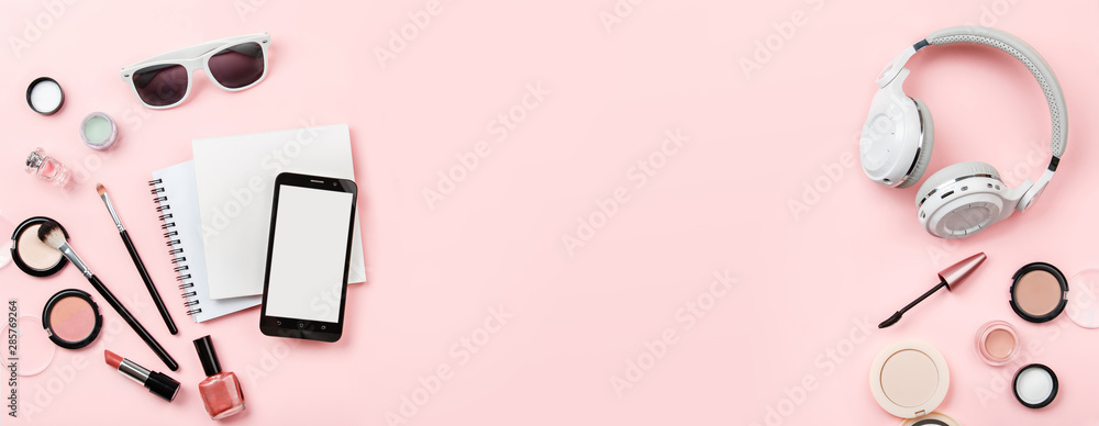 Banner mock up, woman's cosmetics and phone on pink background. Headphones, notebook and decorative cosmetics: highlighter, concealer, rouge, and brushes for face make up. Copy space. 'To do' list Banner mock up, woman's cosmetics and phone on pink background. Headphones, notebook and decorative cosmetics: highlighter, concealer, rouge, and brushes for face make up. Copy space. 'To do' list