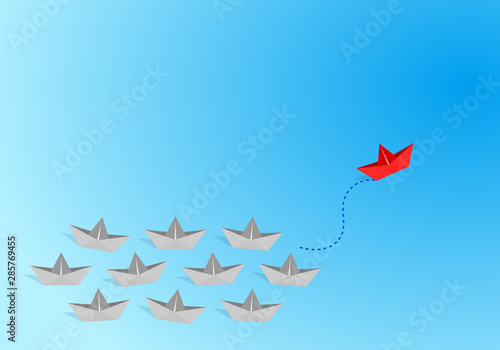 Red origami paper boat leading gray staff ones go on the route on blue background. Leadership and teamwork concept.