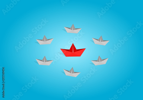 Red origami paper boat leading gray staff ones go on the route on blue background. Leadership and teamwork concept.