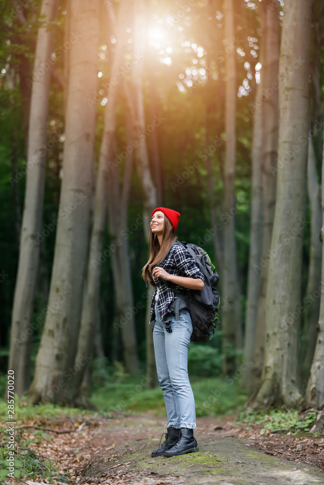 Skinny young woman is hiking by the wooden path in the middle of lush pine forest Skinny young woman is hiking by the wooden path in the middle of lush pine forest