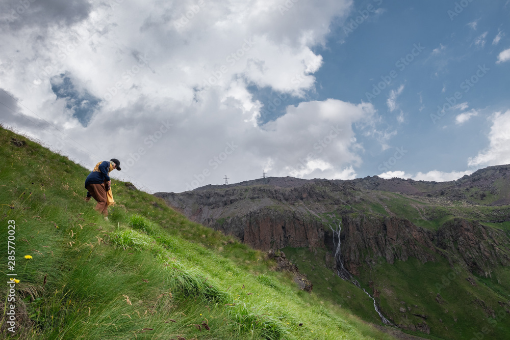 girl descends alone from a green hill in the mountains