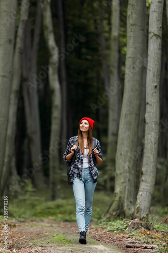 Satisfied traveler with gentle smile walking across green forest, spending summer vacation actively, explores nature alone © proimagecontent