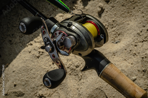 Fishing from the shore. Rigged up baitcasting reel ready to catch a pike. Close-up photo