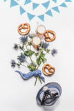 Oktoberfest composition with traditional Bavarian white blue fabric , decoration, pretzel , cups of draft beer, Bavarian hat and bunch of alpine flowers on white background. Top view. Flat lay