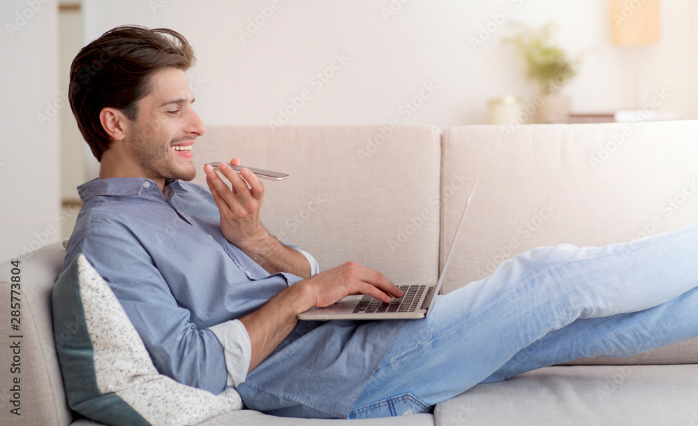 Cheerful Guy Talking On Phone Using Laptop Lying On Couch Cheerful Guy Talking On Phone Using Laptop Lying On Couch