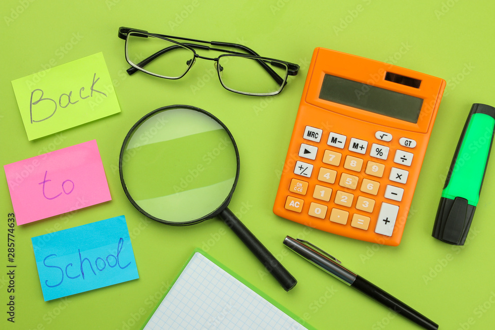back to school. stationery, school supplies text on bright multi-colored stickers, a calculator, magnifier, and glasses on a bright green background. top view back to school. stationery, school supplies text on bright multi-colored stickers, a calculator, magnifier, and glasses on a bright green background. top view