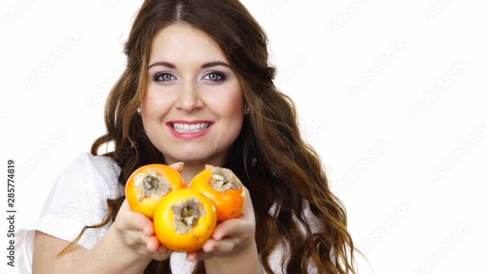 Woman toothy smile brunette girl holding persimmon kaki fruits in hands, isolated on white. Healthy eating, vegetarian food, diet concept Woman toothy smile brunette girl holding persimmon kaki fruits in hands, isolated on white. Healthy eating, vegetarian food, diet concept