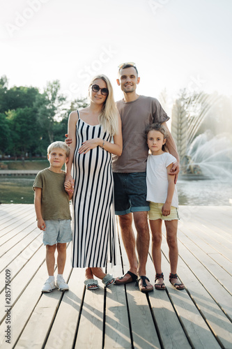 Photo of happy family with children on walk in park on background of fountain