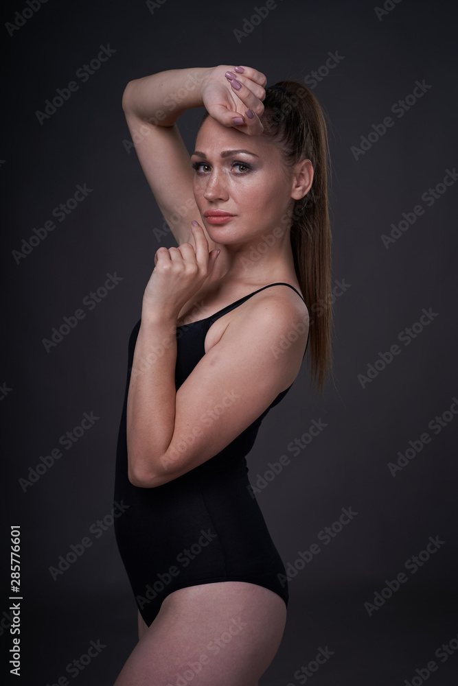 flexible sexy girl poses on a black grey background in the fitting clothes baud