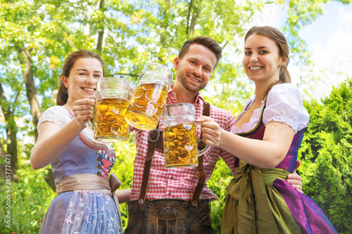 Young people in Tracht, Dindl and Lederhosen having fun in Beer garden photo