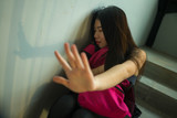 Young beautiful depressed Asian Chinese college student sitting on campus staircase victim of abuse feeling scared and lonely being harassed and bullied