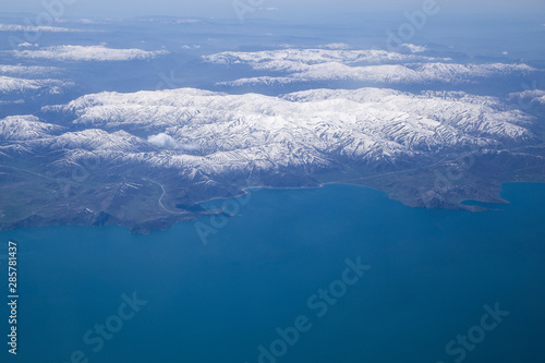 Clouds and mountains covered in snow viewed from inside the aircraft. Travel concept with copy space.