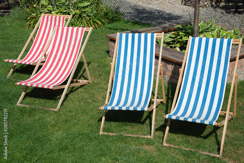 Deckchair chaise chair in café garden park gras, with blue red stripes relax