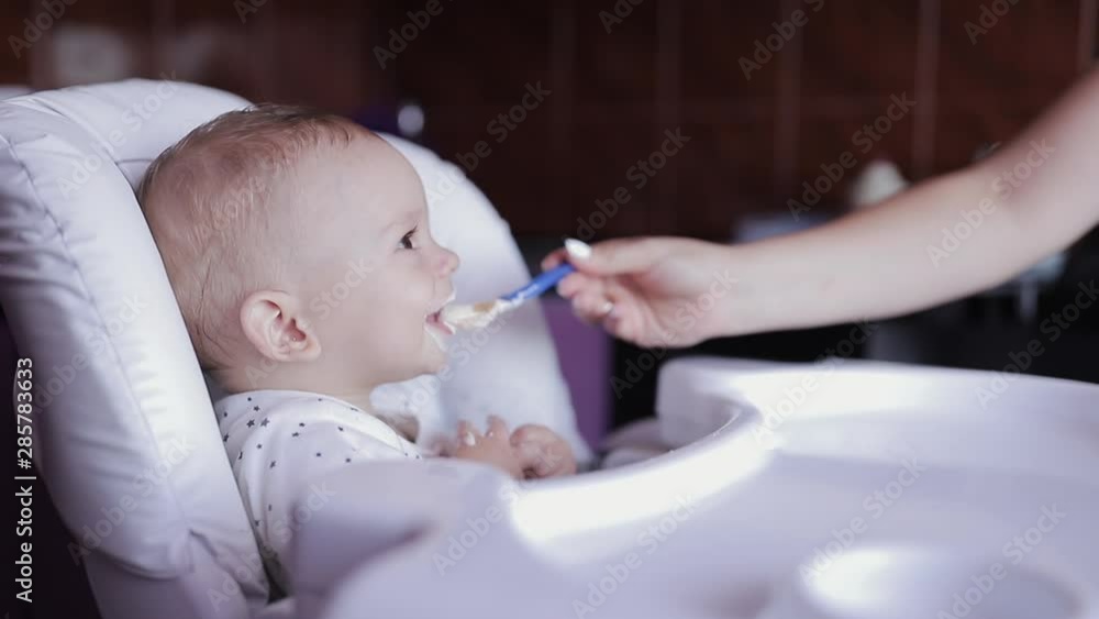 Young happy mother feeds his son baby porridge Young happy mother feeds his son baby porridge