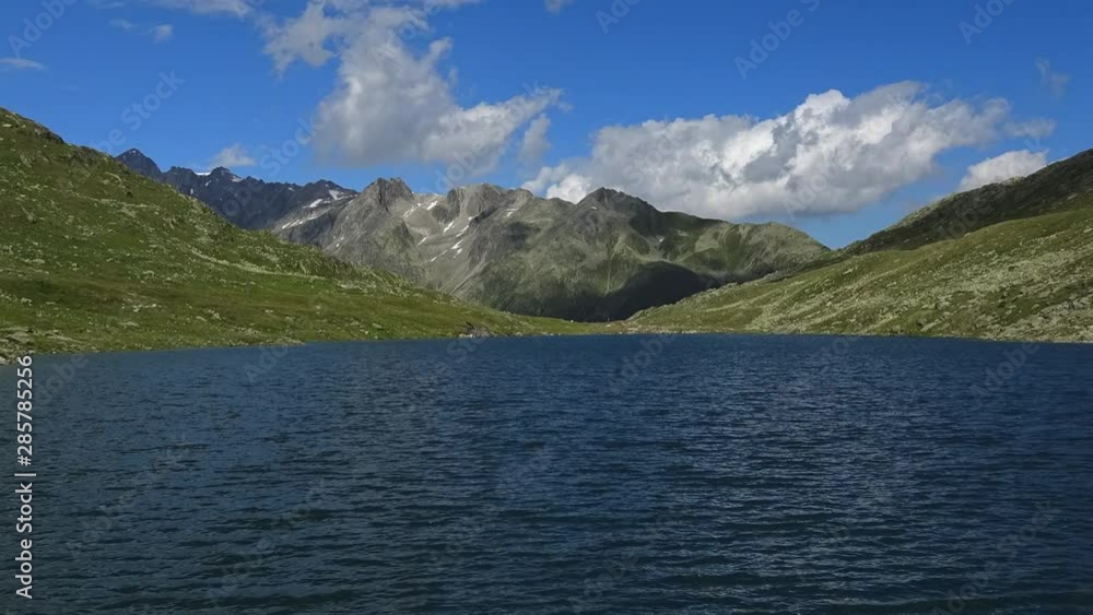 Time lapse view on peak of mountains and lake in Swiss Alps. Summer landscape, sunshine weather, blue sky and sunny day Time lapse view on peak of mountains and lake in Swiss Alps. Summer landscape, sunshine weather, blue sky and sunny day