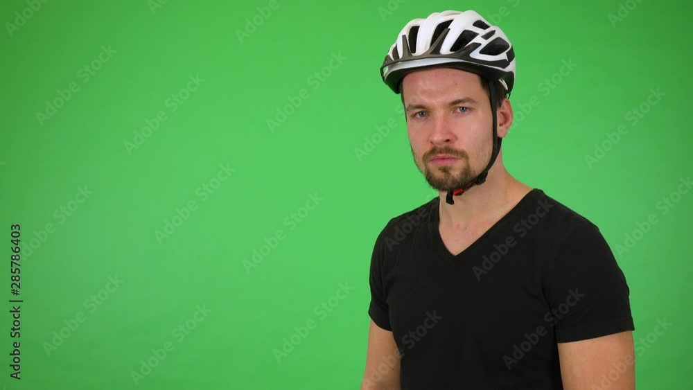 A young handsome cyclist looks seriously at the camera - green screen studio A young handsome cyclist looks seriously at the camera - green screen studio