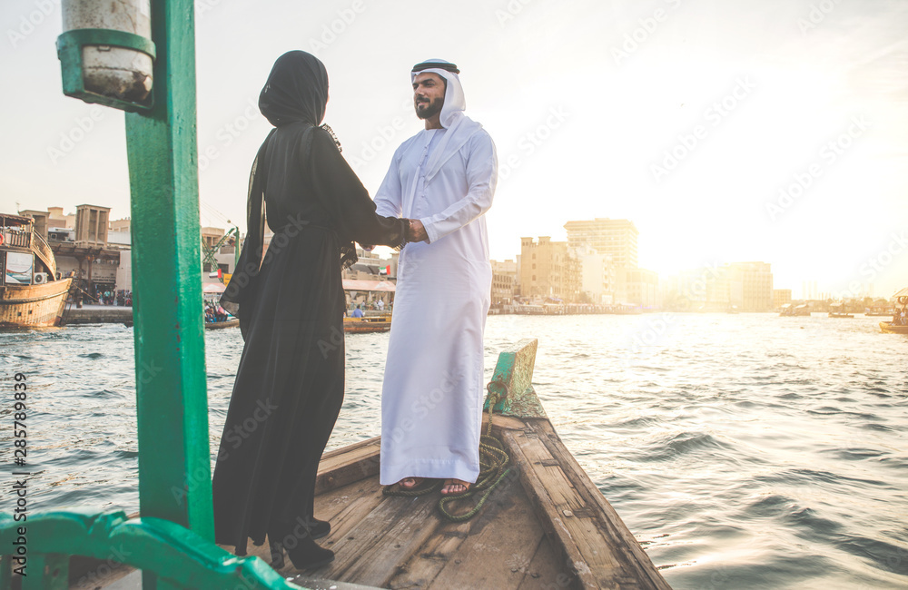 Happy couple spending time in Dubai. man and woman wearing traditional clothes taking a cruise on the river