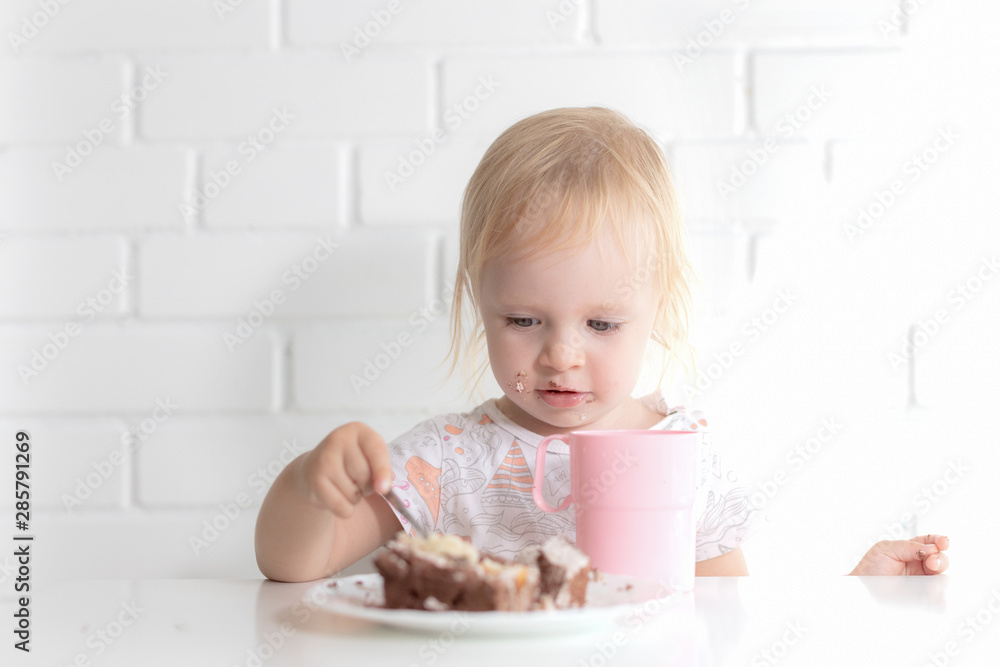 baby girl eating cake sitting at the table baby girl eating cake sitting at the table