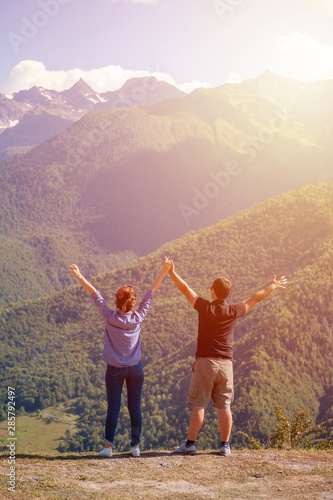 Young, beautiful couple holding rising hands in high mountains of upper Svaneti, Georgia.