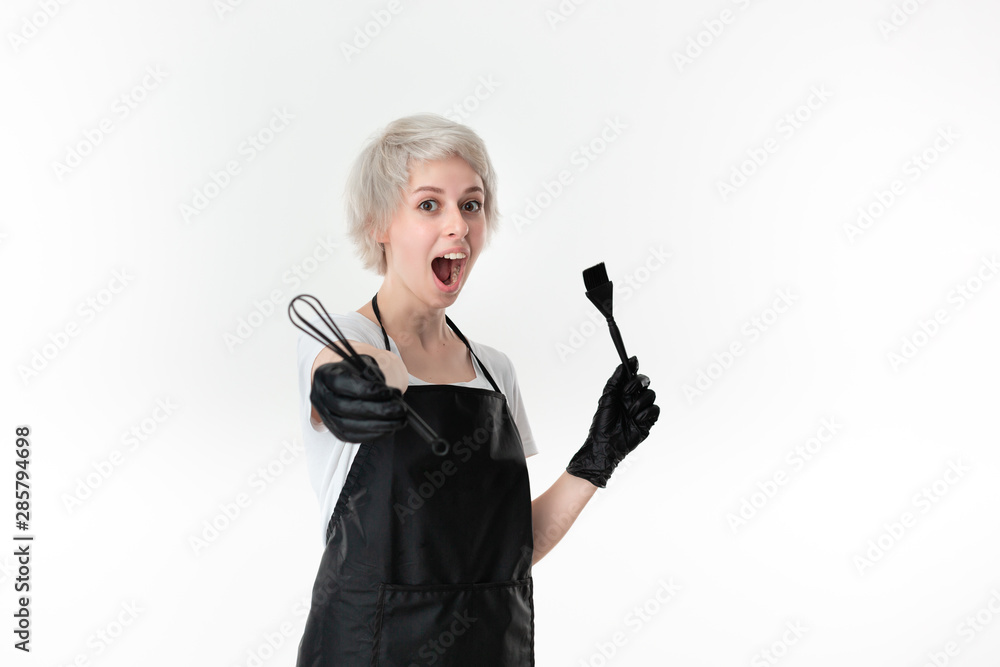 Pretty young hairstylist in a white tee and black apron holding color mixer and paintbrush standing isolated over white background. Pretty young hairstylist in a white tee and black apron holding color mixer and paintbrush standing isolated over white background.
