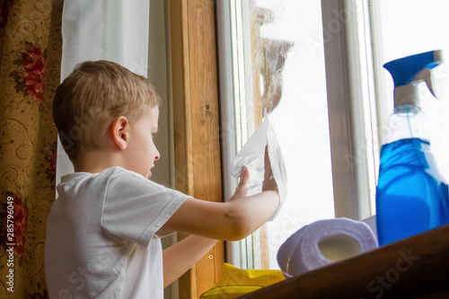 the boy in the yellow gloves washes a window