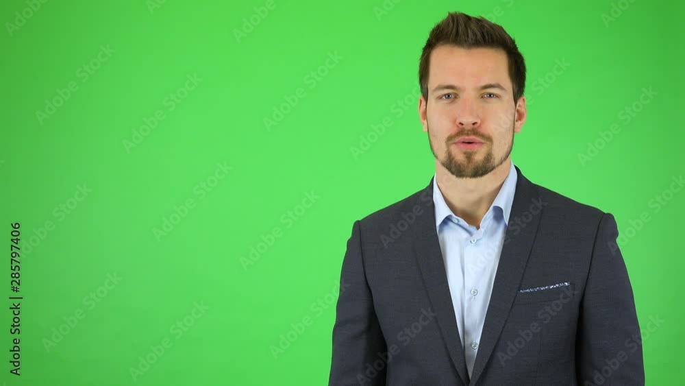 A young handsome businessman talks to the camera with a smile, then turns and walks out of the frame - green screen studio A young handsome businessman talks to the camera with a smile, then turns and walks out of the frame - green screen studio