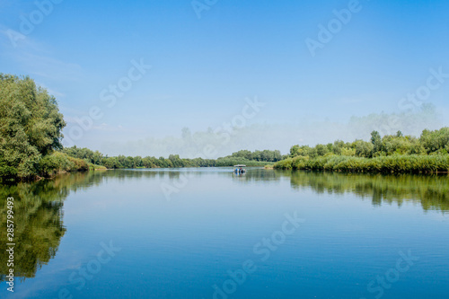 Fototapeta Naklejka Na Ścianę i Meble -  Blue beautiful sky against the background of the river. Clouds are displayed in calm water. On the horizon, the green bank of the Dniester, place for fishing