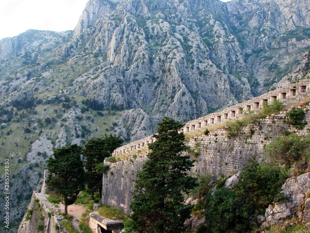 Obraz premium Landscape from the top of a mountain on the surviving walls of a medieval fortress surrounded by high inaccessible rocks covered with poor vegetation.