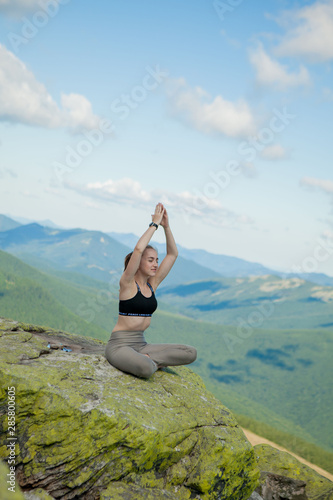 Girl doing yoga exercise lotus pose at the top of the mountain.