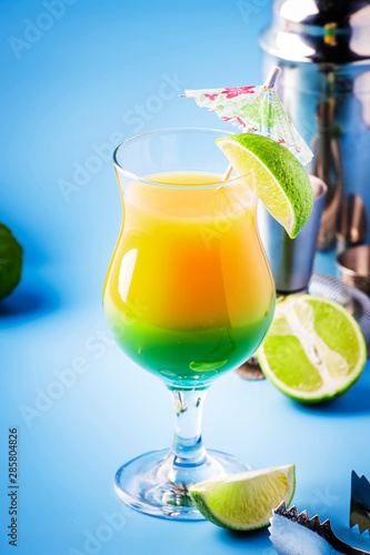 Double layer green yellow alcoholic cocktail with mango juice  rum  liqueur  lime and ice  blue background  copy cpase