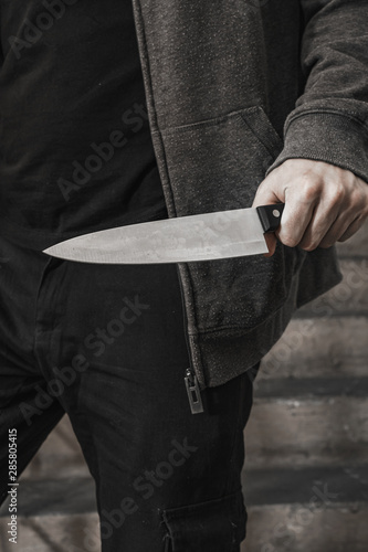 man with a knife i on the landing. the killer hides with covers the knife before the attack. topics of violence and murder. thief, rapist, maniac