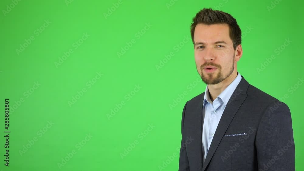 A young handsome businessman talks to the camera, pointing at bullet-point texts sliding toward him - green screen studio A young handsome businessman talks to the camera, pointing at bullet-point texts sliding toward him - green screen studio