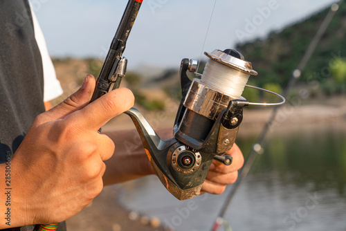 Male hand holding fishing rod and reeling the other hand.