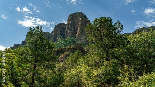 A mountain stands tall above the green landscape and blue sky 