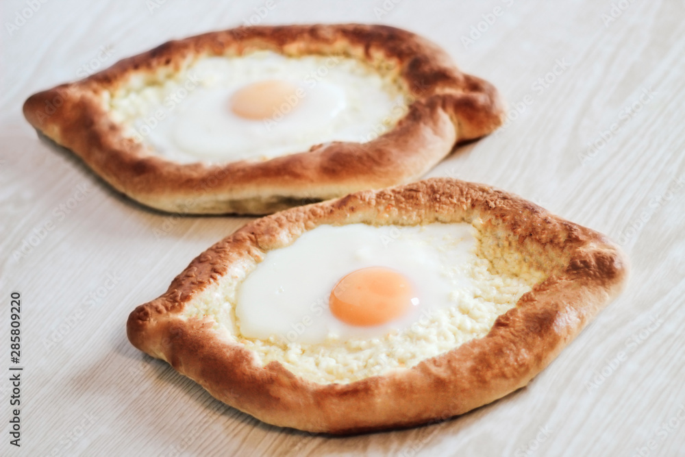 Homemade Ajarian Khachapuri with Suluguni Cheese Filled with a  Egg and Melted Butter Close Up on the white wooden background
