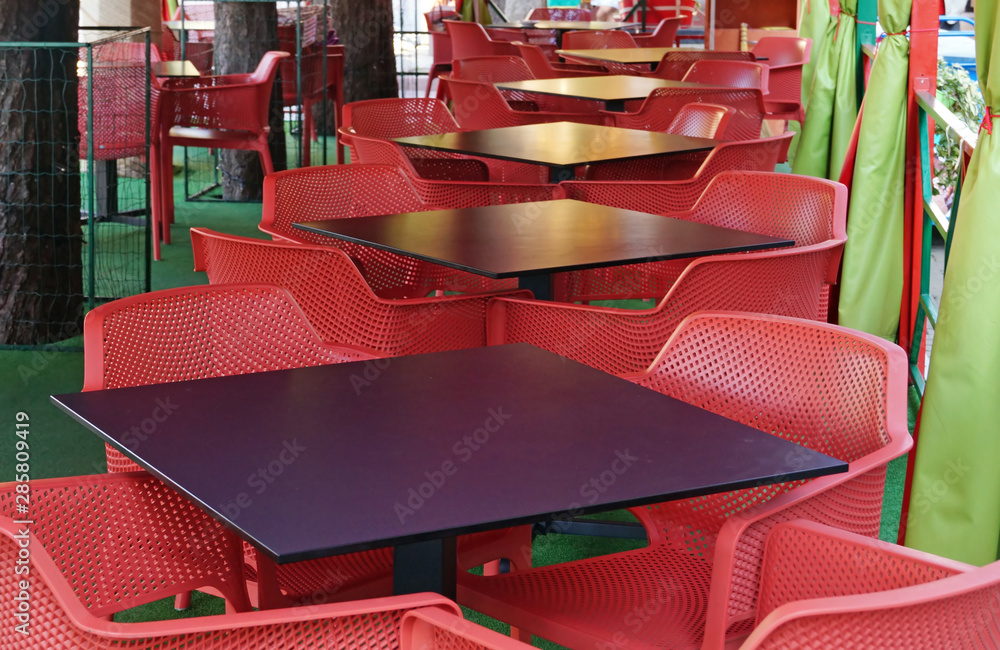 Tables and chairs on empty terrace of a street cafe.