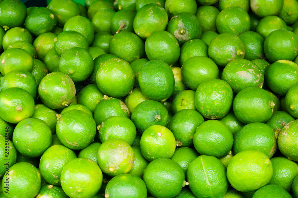 Fresh lemon green skin after harvesting on the floor for distribution.Green fresh limes at maket Fresh lemon green skin after harvesting on the floor for distribution.Green fresh limes at maket