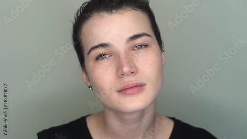 Young brunette woman with closed eyes opens her eyes. close-up