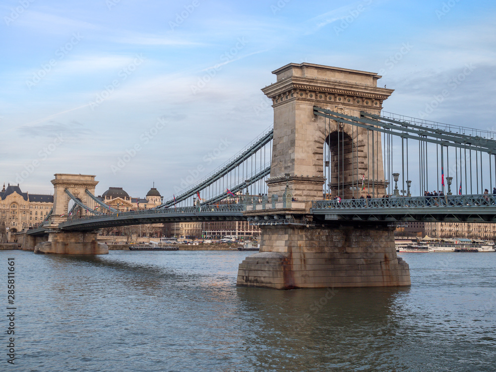 Obraz premium Budapest, Hungary - Mar 9th 2019: The Széchenyi Chain Bridge is a suspension bridge that spans the River Danube between Buda and Pest, the western and eastern sides of Budapest, the capital of Hungary