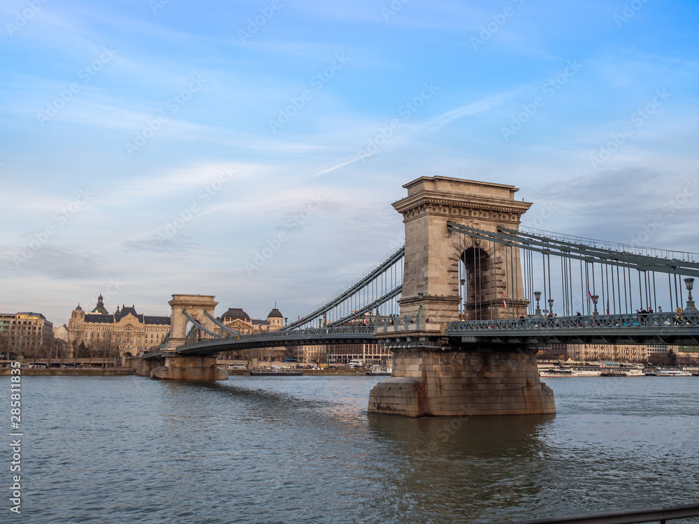 Obraz premium Budapest, Hungary - Mar 9th 2019: The Széchenyi Chain Bridge is a suspension bridge that spans the River Danube between Buda and Pest, the western and eastern sides of Budapest, the capital of Hungary