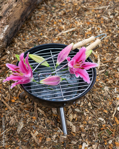 Garden installation with pink lily flowers in barbecue grill.