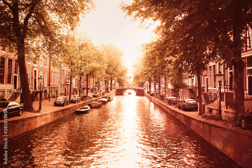 Amsterdam seen from the canal with boats and architecture in view, This image has a retro tone