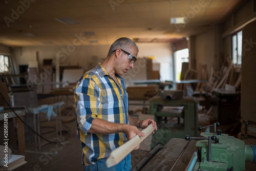 a carpenter measures a massive piece of wood