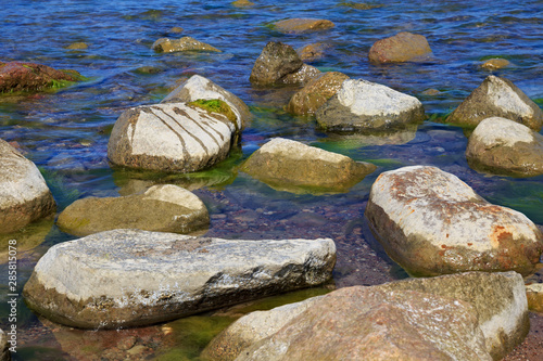 Large stones in the blue water of the sea.