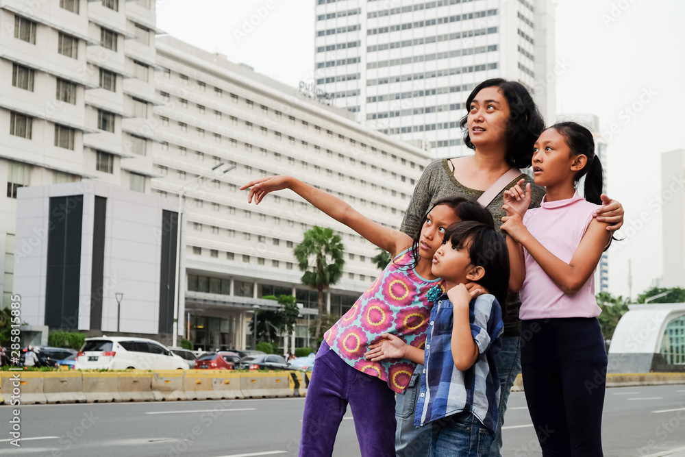 Asian Mother with Three Children Having Fun Traveling Around At City Center Looking At City Scene