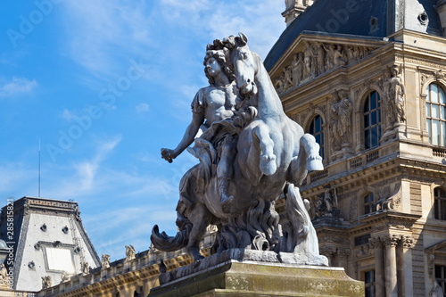 Sculpture of the Louis XIV king near the Louvre buildings in Paris, France. Is the world's largest art museum and is housed in the Louvre Palace, originally built in the 12-13 century.