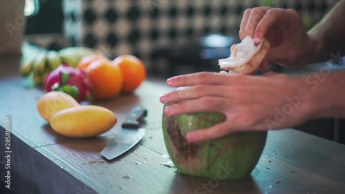 Man Opens Young Green Big Coconut in Kitchen with Coconut Water in Slow Motion.